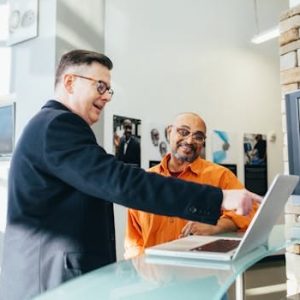 Two businessmen having a lively discussion in a modern office setting, pointing at a laptop screen.