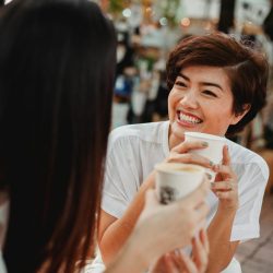Two women enjoying a joyful coffee conversation outdoors at a café